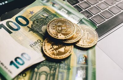 Euros und Münze vor einem Laptop